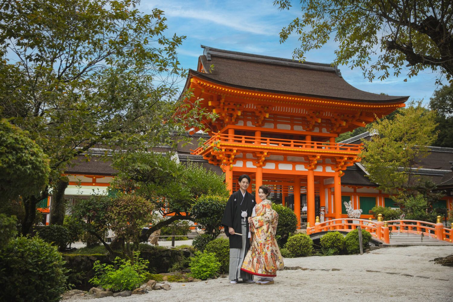 上賀茂神社の桜門を背景に色打掛の花嫁と新郎