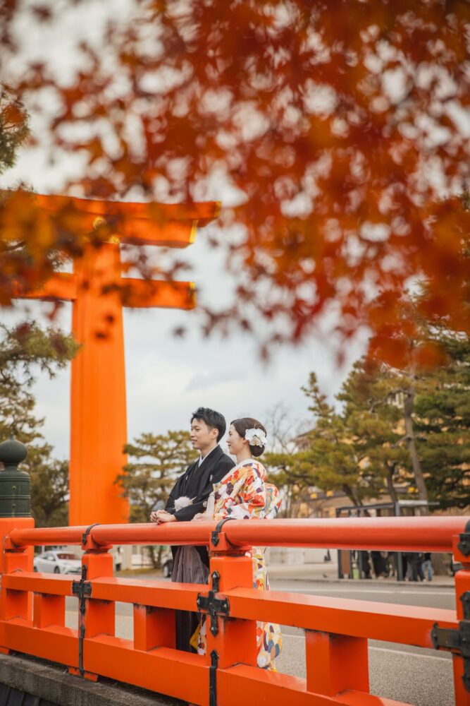 平安神宮の大鳥居を背景に紅葉との色打掛の花嫁と新郎