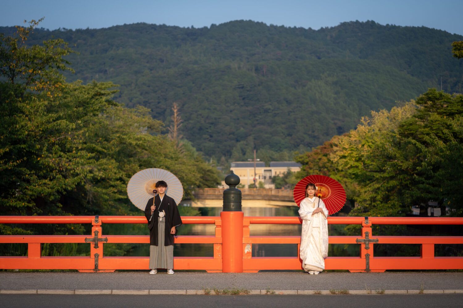 平安神宮の慶流橋での紅白の番傘をもて白無垢の花嫁と新郎