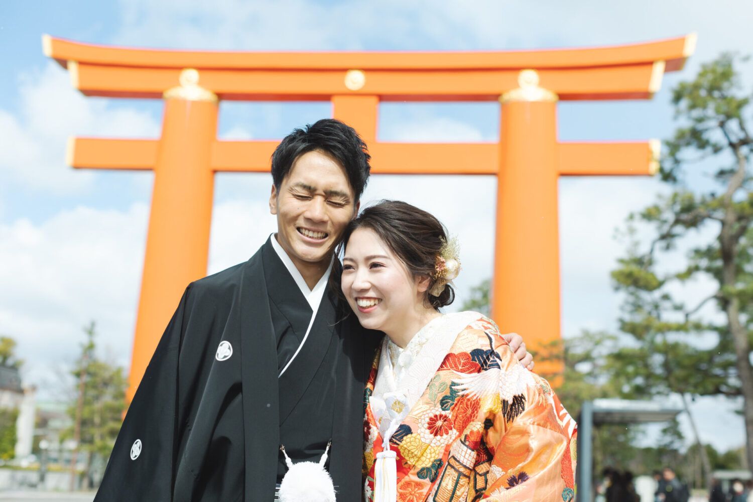 平安神宮の大鳥居を背景に色打掛の花嫁と新郎