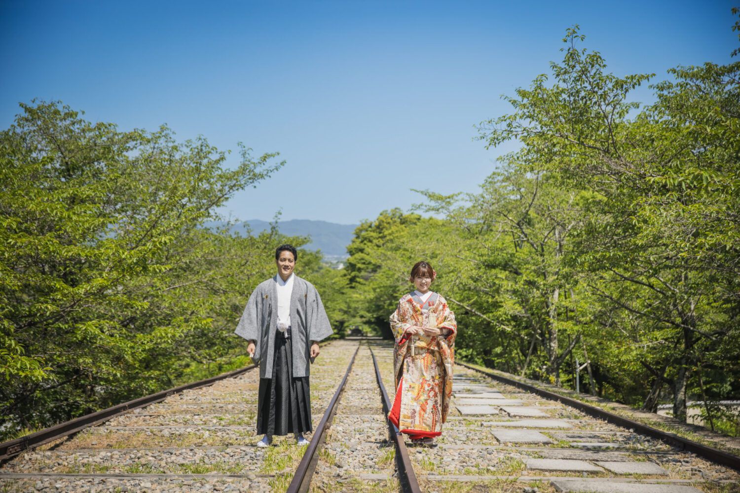 インクラインで青空と緑の中で色打掛の花嫁と新郎