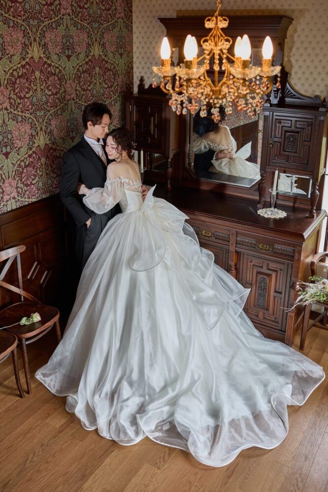 英国アンティークスタジオでシャンデリアをアクセントにカンタベッラドレス(Cannta Bella Dress）の花嫁と新郎