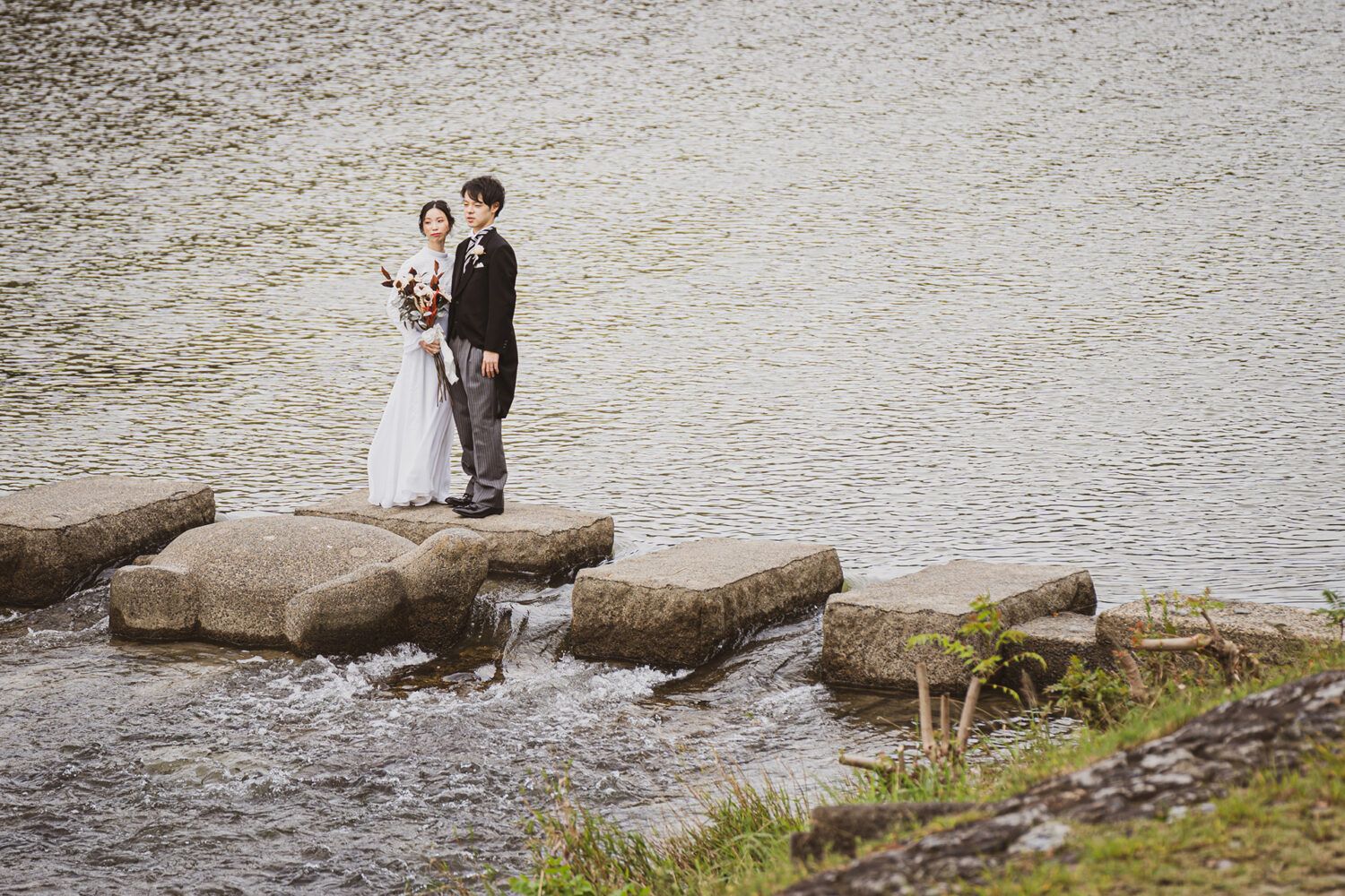 鴨川のせせらぎの石の上でのヴィンテージドレスでの花嫁と新郎