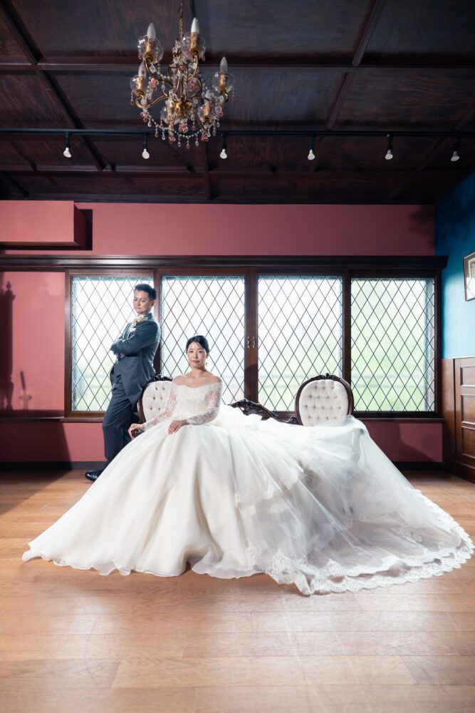 英国アンティークスタジオのピンクの壁紙とアンティークの燭台に座ってカンタベッラドレス(Cannta Bella Dress）の花嫁と新郎