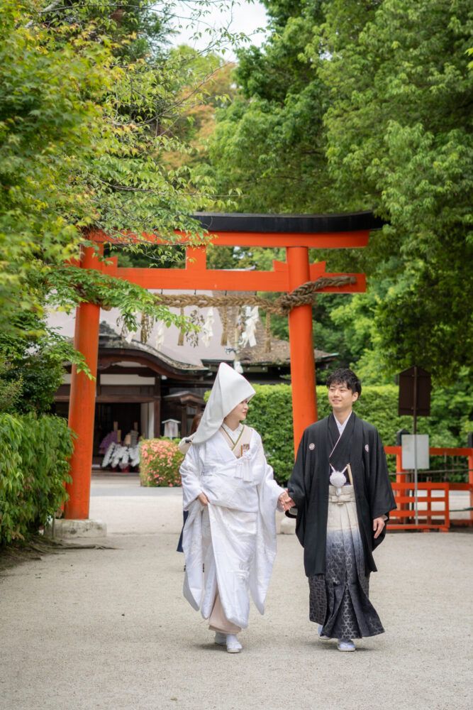 上賀茂神社の西の鳥居から歩む綿帽子姿の白無垢の花嫁と新郎