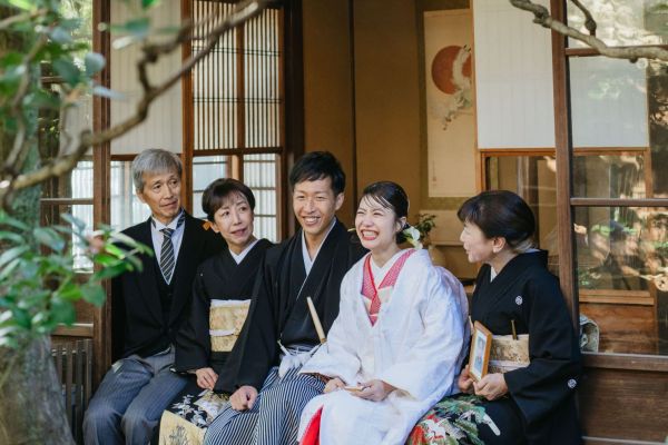京町家の縁側で、笑顔のご両親と和装姿の新郎新婦。