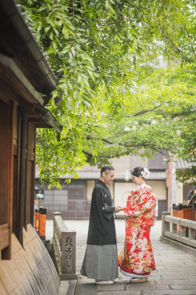 祇園の巽橋で向かい合う色打掛の花嫁と新郎