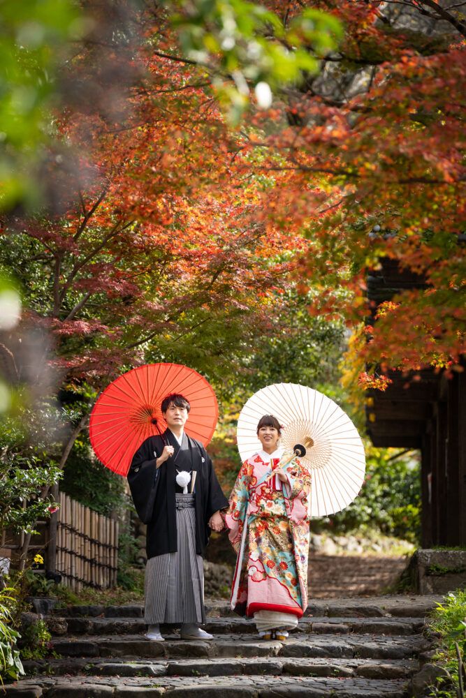 円山公園の石会談を紅白の番傘を持って歩く新郎新婦