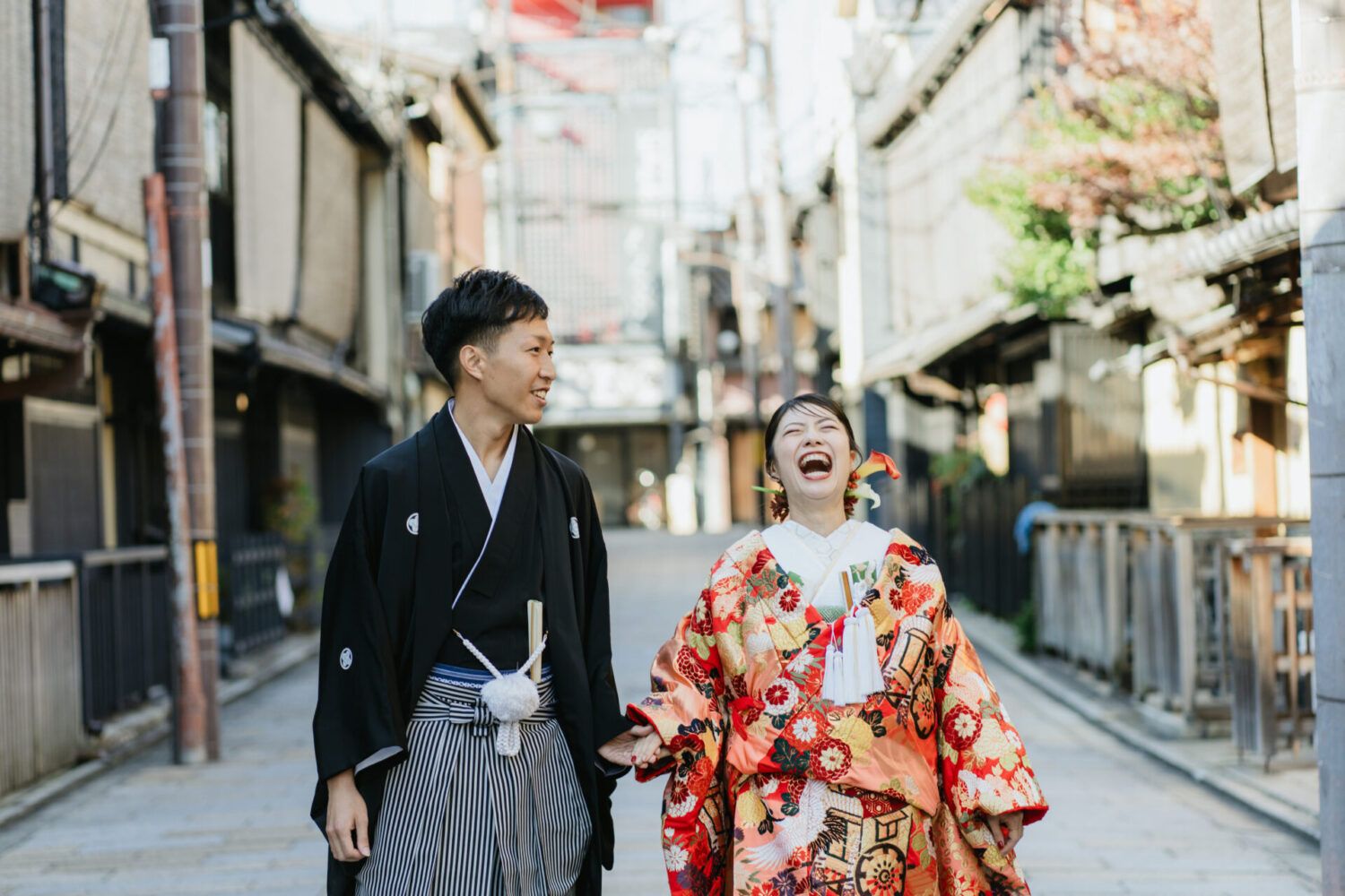 祇園街を笑顔で仲良く色打掛で歩く花嫁と新郎