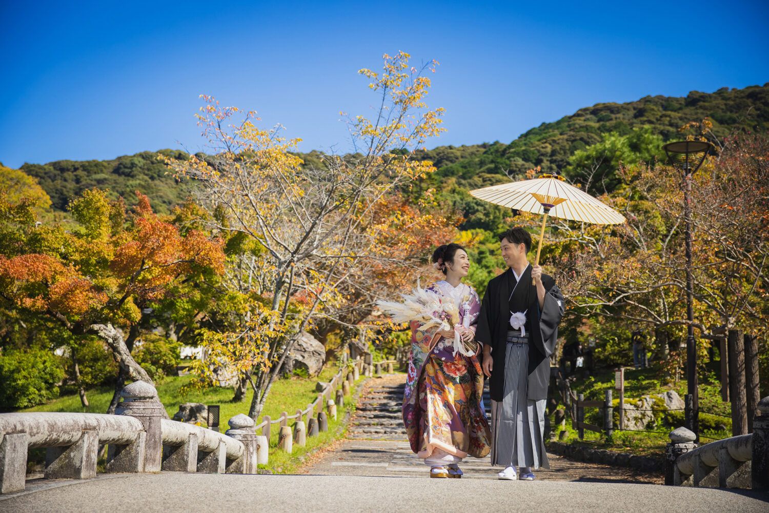 円山公園の紅葉の中を色打掛で歩く新郎新婦