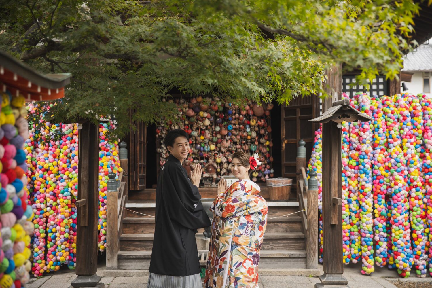八坂庚申堂のカラフルなくくり猿の前で色打掛の花嫁と新郎
