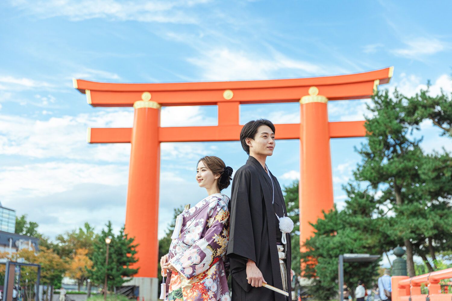 平安神宮の大鳥居を背景に色打掛の花嫁と新郎