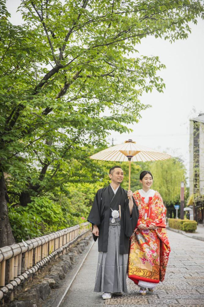 祇園の石畳を白番傘での色打掛の花嫁と新郎