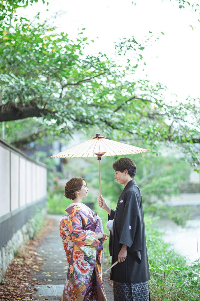 平安神宮周辺の白川疎水で白番傘で見つめあう新郎新婦