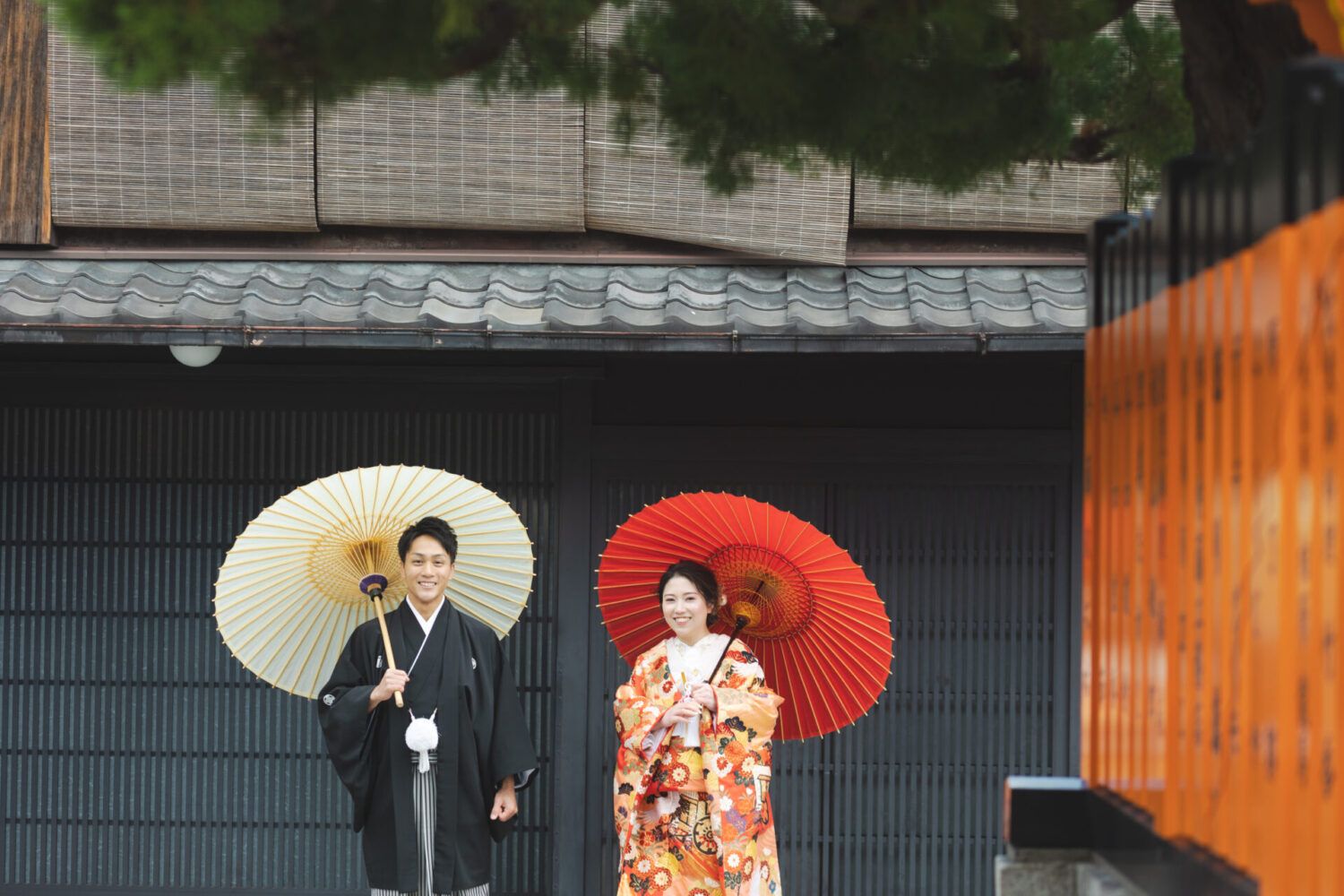 祇園街を紅白の番傘を持った色打掛の花嫁と新郎