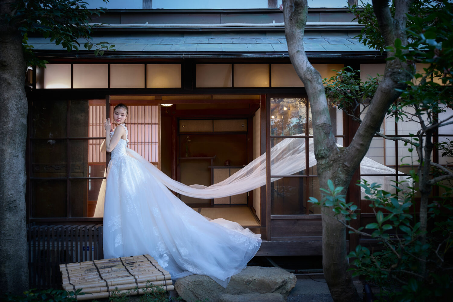 京町家の廊下で長いベールを風になびかせているウェディングドレスの新婦