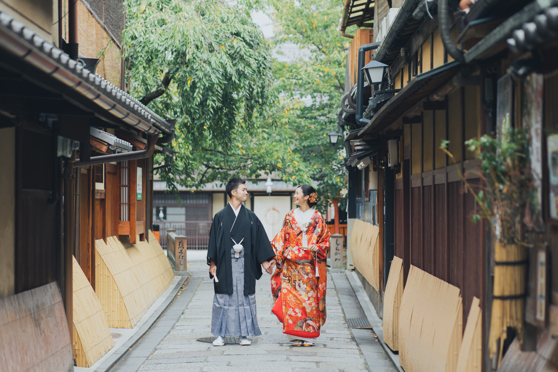 祇園の町並みを手をつないで歩くお二人。風情ある石畳、町家の立ち並ぶ祇園白川はお二人の和装コーディネートにぴったりです。
