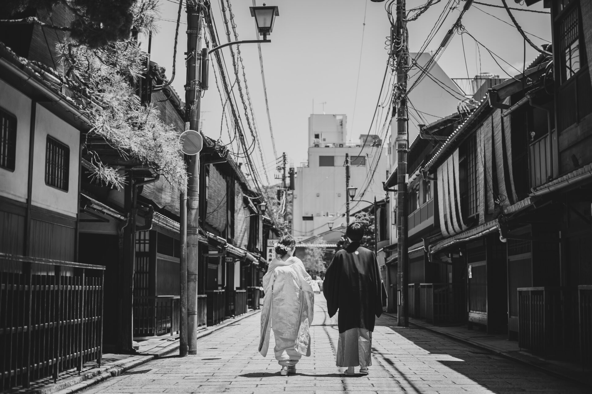祇園の街並みを仲良く歩くお二人の後ろ姿。白黒写真もレトロで素敵ですね。