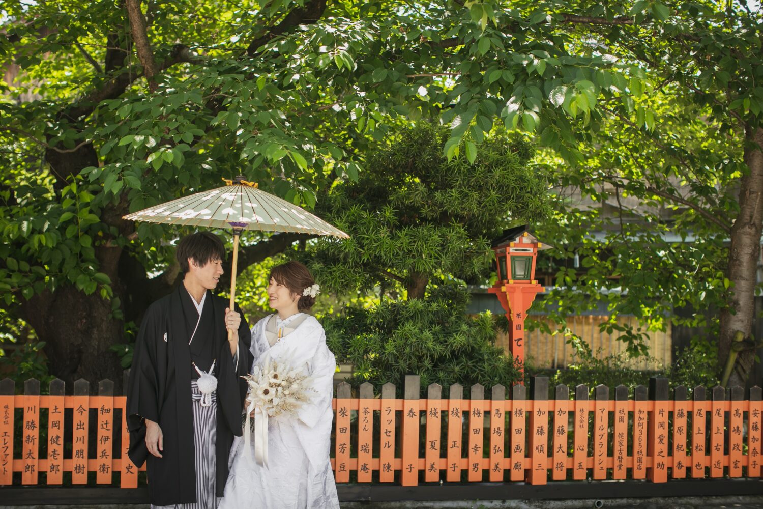 上賀茂神社の境内で番傘を持つ和装姿の新郎新婦。