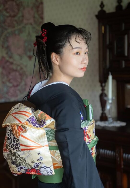 アンティーク家具のある部屋で撮影した、黒引き振袖の帯結びとヘアセットの後ろ姿