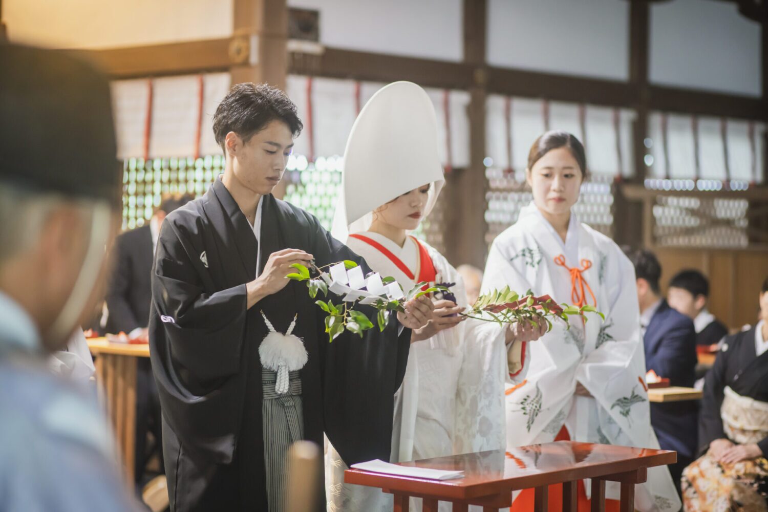 岡崎神社での神前式。白無垢と綿帽子の花嫁と紋付袴の新郎が玉串を手に儀式に臨む場面