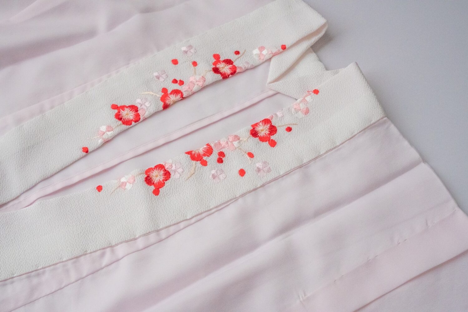 白地に赤い梅の刺繍が施された半襟のディテール。