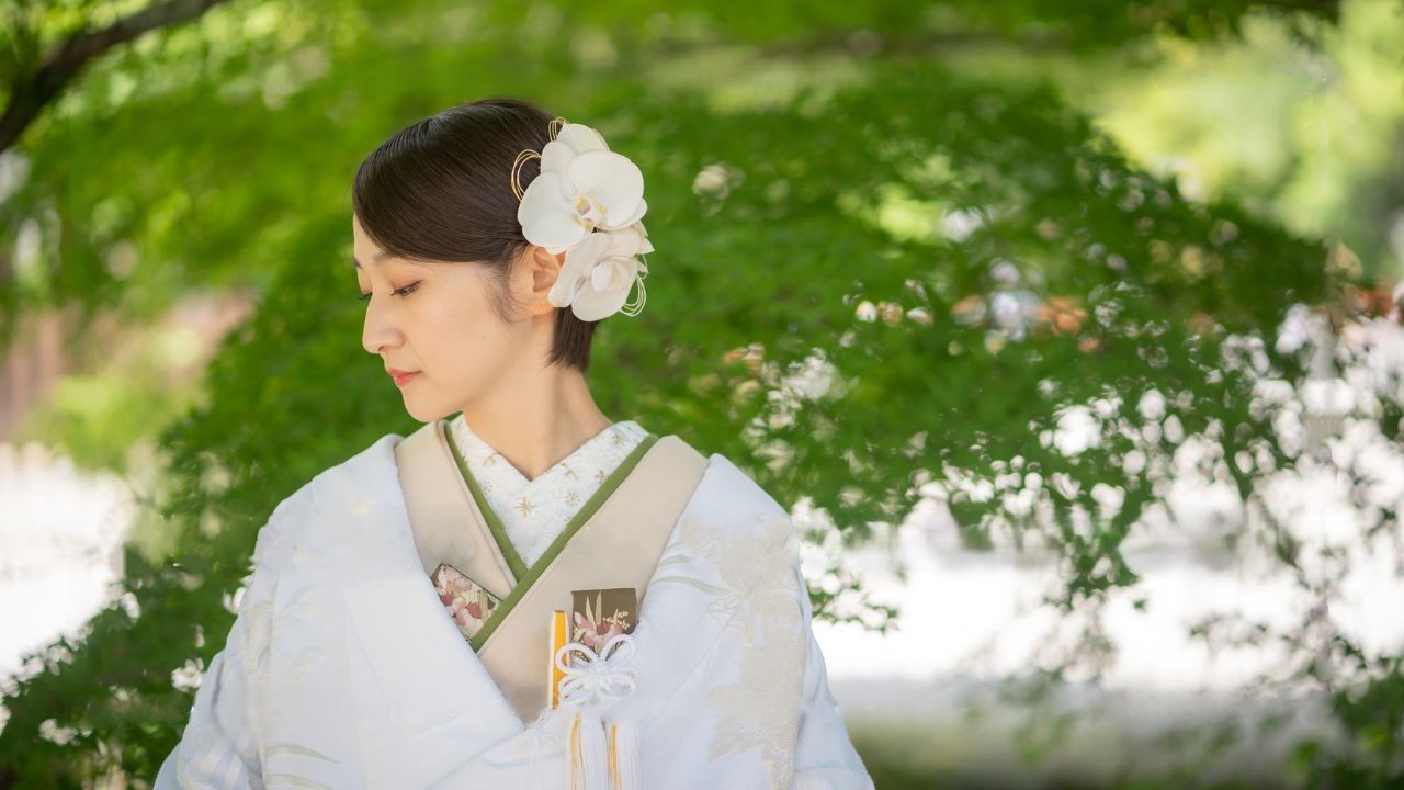 青紅葉の中でほほ笑む、白無垢姿のショートヘアの新婦。