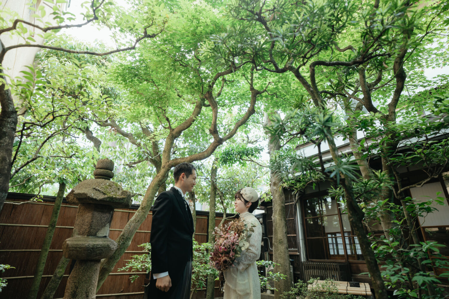 花束を持って日本庭園で向かい合う新婦と新郎