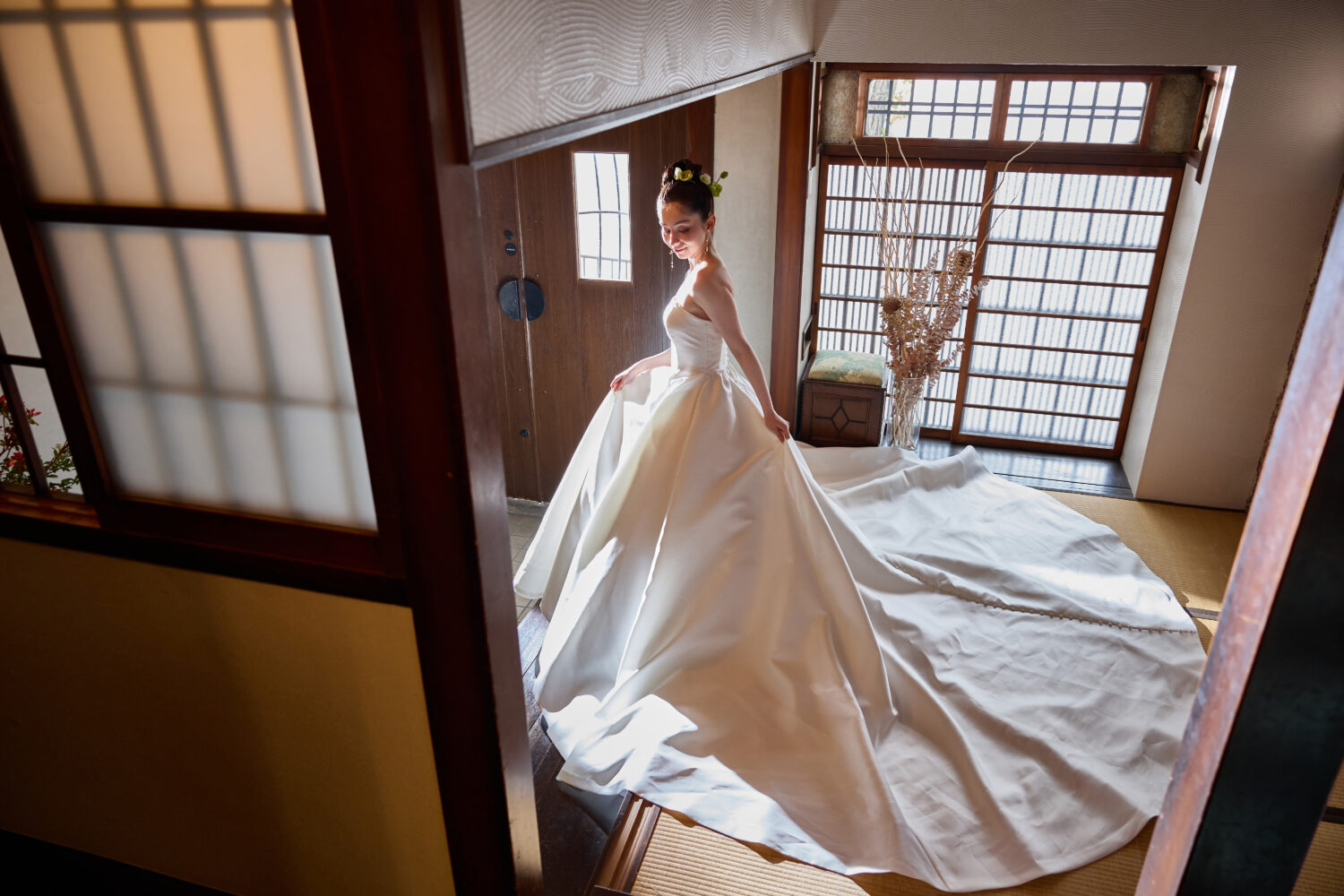 京町家の畳の間で、障子越しの光を受けながらトレーンを大きく広げたサテンドレスの花嫁