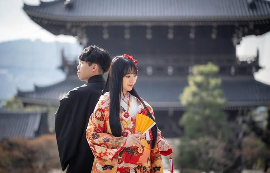 金戒光明寺の御影堂を背に、扇を持つ赤い色打掛の新婦と黒紋付の新郎